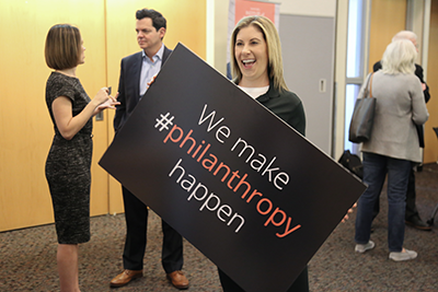 Panel attendee posing with Make Philanthropy Happen sign