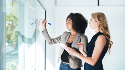 Two business women looking at a board