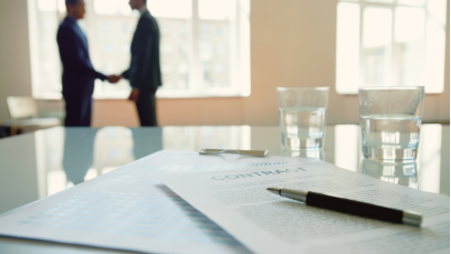 Image of a work contract and two professionals shaking hands