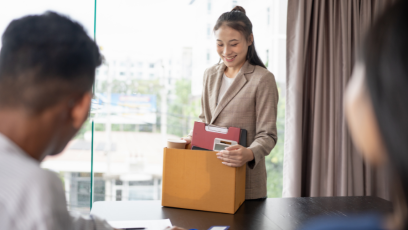 A woman hands in her resignation to her superiors as she prepares to leave with a box of her things.