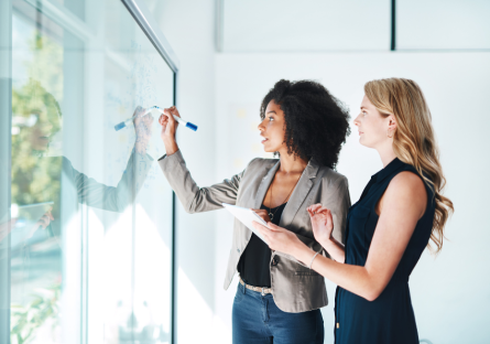 Two business women looking at a board
