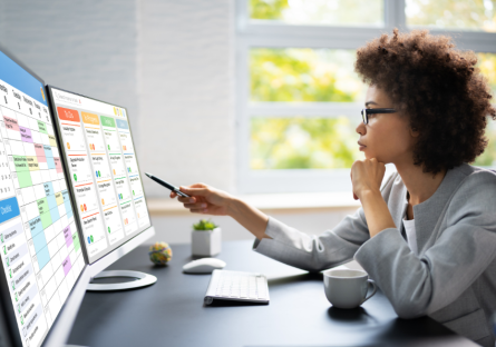 A woman sits in front of her computer contemplating her online calendar and her tasks list.