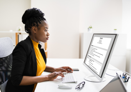 A woman sits in front of her computer, using AI to craft her resume.