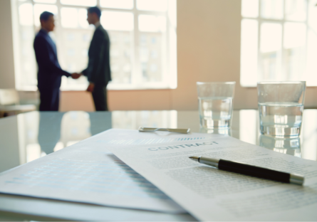 Image of a work contract and two professionals shaking hands