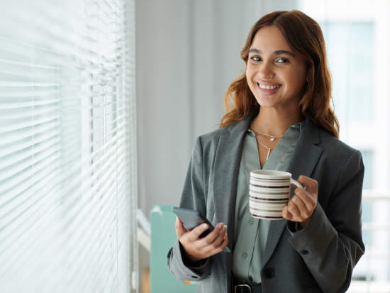 Female HR professional holding a coffee mug and cell phone