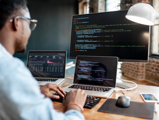 Business man typing while using a laptop and monitor