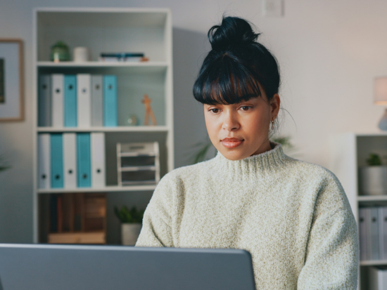 Smiling professional woman working at a desktop computer in a modern office setting.