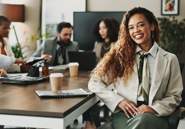 Young smiling professional sitting at table with colleagues in the background