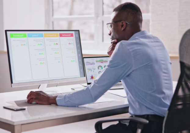Male project manager working on a planning software on a computer in an office setting.