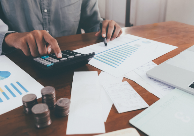 Professional working on a calculator while comparing a graph on a piece of paper.
