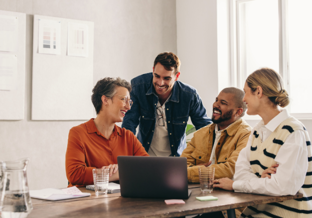 Group of professionals talking and laughing over a laptop