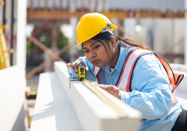 Woman in hard hat using a measuring tape